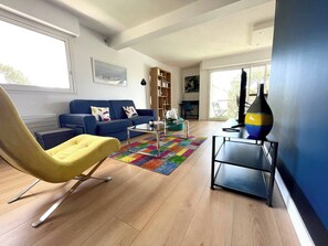 Una sala de estar moderna con un sofá azul, un sillón amarillo, una mesa de centro y una estantería.
