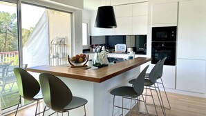 Une cuisine moderne avec un îlot central en bois, des tabourets de bar et une grande fenêtre.