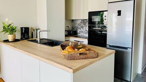 Cuina moderna amb nevera d'acer inoxidable, forn integrat i cafetera a la tauleta.