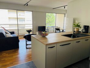 A modern kitchen with a wooden countertop, a sink, and a dining area with a table and chairs.