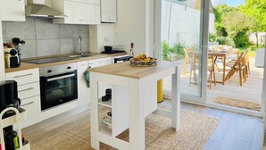 Una cocina moderna con armarios blancos, encimera de madera y un comedor con mesa y sillas.