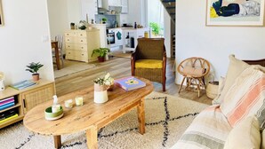 Una sala de estar con una mesa de centro de madera, un sofá, una mesa de comedor y una cocina al fondo.