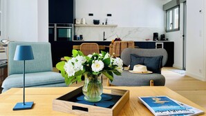 Un moderno salón con un sofá, una mesa de centro con un florero, una lámpara y una revista.