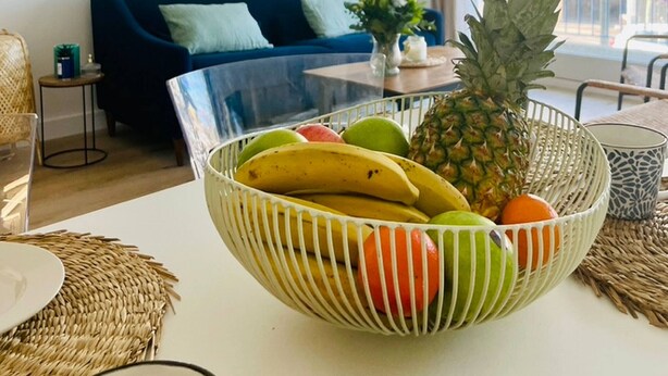A living room with a blue sofa, a white coffee table with a fruit bowl, and a large window. - Appartement La baule "Le 30" (La Baule-Escoublac)