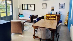 Uma sala de jantar com uma mesa de madeira, cadeiras, um sofá e um abajur.