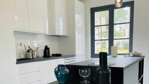 Cozinha moderna com armários brancos, bancada preta e luminárias pendentes.