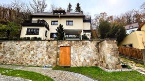 Ein zweistöckiges Haus mit einer Steinmauer, einer Holztür und einem gepflasterten Auffahrt.