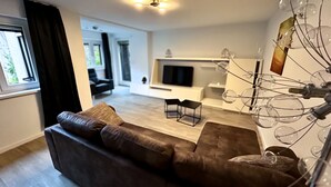 Ein modernes Wohnzimmer mit einem braunen Sofa, einem kleinen Tisch und einer dekorativen Leuchte.