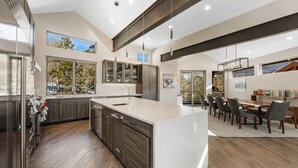 Une cuisine moderne dotée d’un grand îlot central, de meubles en bois foncé et d’un coin repas avec une table et des chaises.