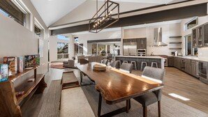 Une cuisine spacieuse avec une longue table en bois, des appareils modernes et un grand îlot central.