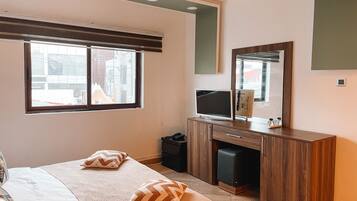 Un dormitorio con cama, dos almohadas, cómoda, televisor y espejo.
