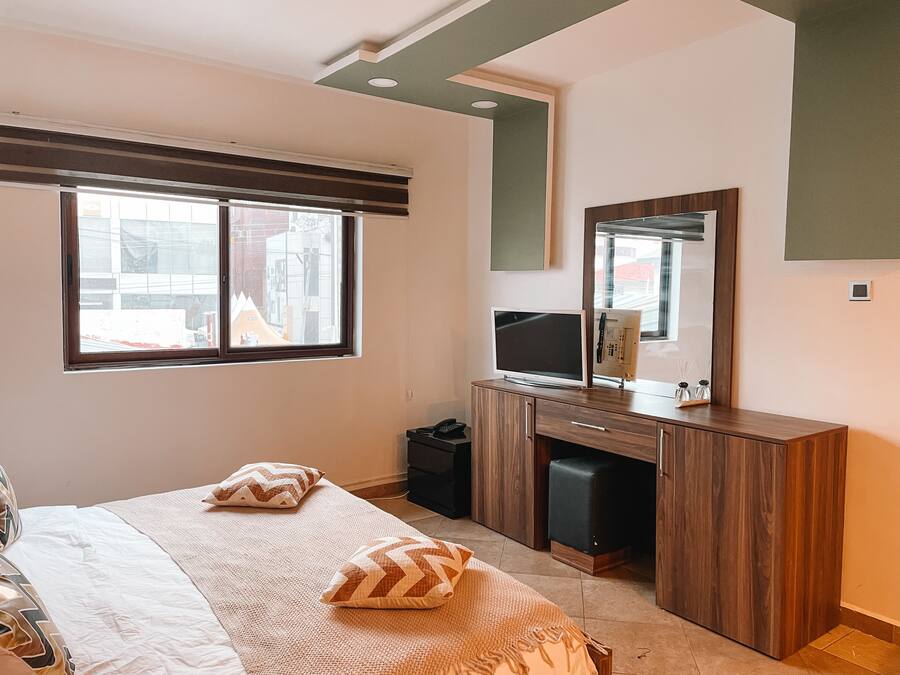 Un dormitorio con cama, dos almohadas, cómoda, televisor y espejo.