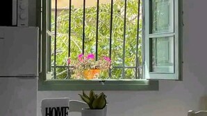 Une pièce avec une fenêtre, une table recouverte d’une nappe à carreaux, une chaise et un panneau indiquant « MAISON ».