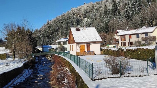 A residential area with houses, a snow-covered landscape, and a small stream.