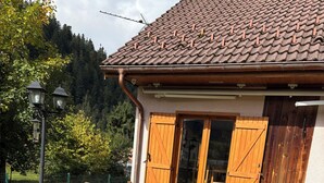 A house with a tiled roof, wooden shutters, and a wooden fence.