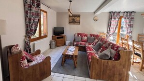A cozy living room with a sofa set, a wooden coffee table, and a television.