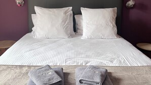 A neatly made bed with white linens and two folded towels on a textured rug. - Résidence thermale de la Chaldette (Brion)