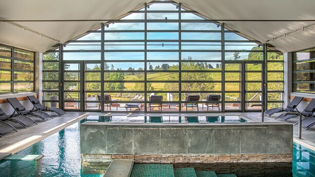 A pool area with a view of a green landscape through large windows. - Résidence thermale de la Chaldette (Brion)