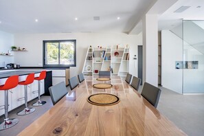 Eine moderne Küche mit einem großen Esstisch, roten Barhocker und einem Bücherregal.