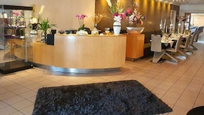 A reception area with a wooden counter, potted plants, and a black rug. - Hotel & Landgasthof Zum Wendelwirt (Germaringen)