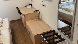 A compact hotel room with a wooden desk, a mounted TV, a painting on the wall, and a bed with a mirror. - Hotel & Landgasthof Zum Wendelwirt (Germaringen)