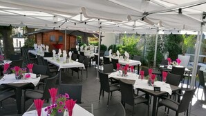 An outdoor restaurant with tables set under white canopies, each with pink napkins and a small flower arrangement. - Hotel & Landgasthof Zum Wendelwirt (Germaringen)