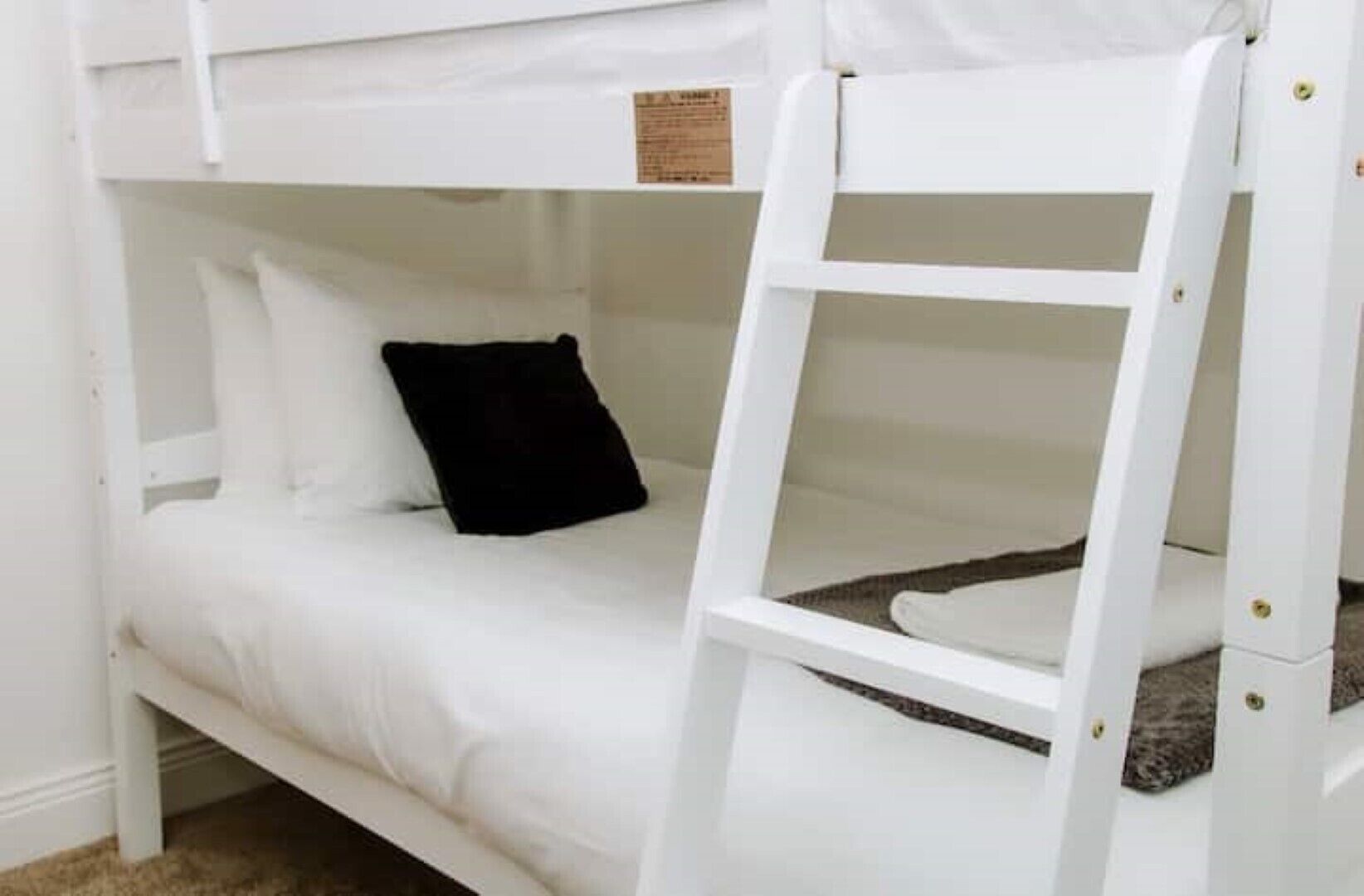 Un letto a castello con biancheria da letto bianca e un cuscino nero.