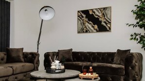 En moderne stue med en mørkebrun sofa, et rundt sofabord og en gulvlampe.
