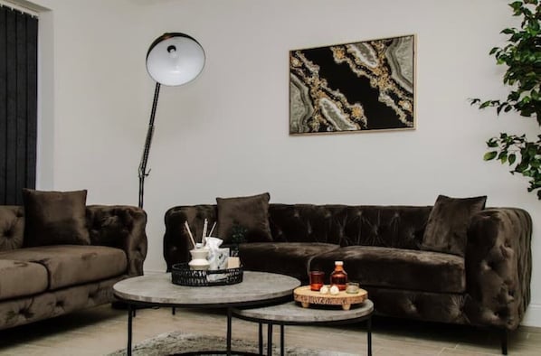 A modern living room with a dark brown sofa, a round coffee table, and a floor lamp.