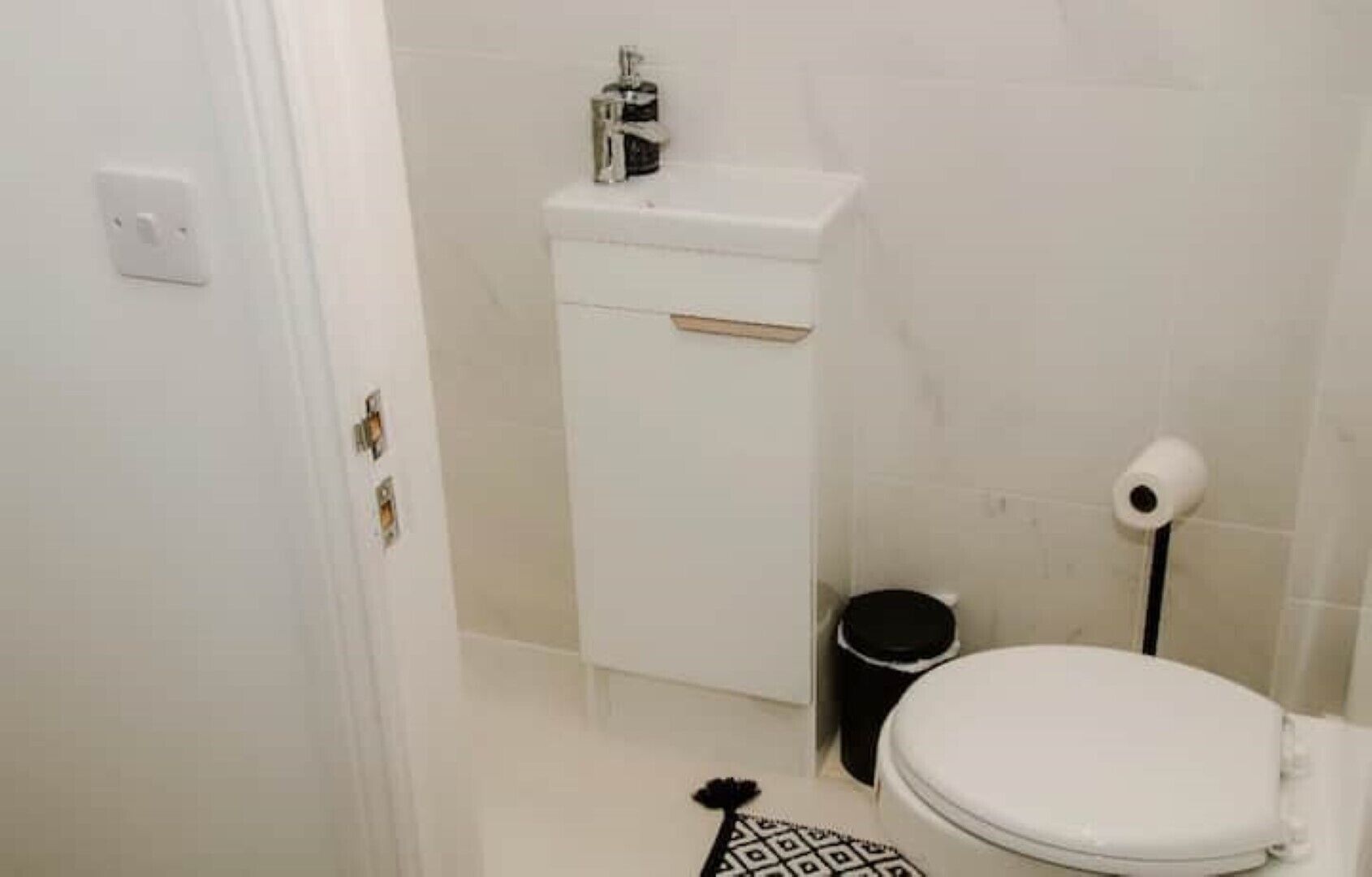 A small, clean bathroom with a toilet, a sink, and a trash bin.