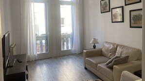 Ett vardagsrum med en beige soffa, en lampa och inramade tavlor på väggen.