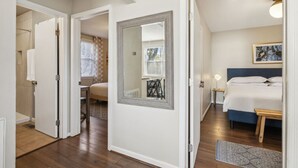 Ein Schlafzimmer mit einem Bett, Nachttischen, einem Spiegel und einem Fenster mit Jalousien.