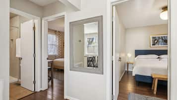 A bedroom with a bed, bedside tables, a mirror, and a window with blinds.