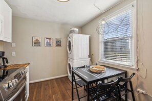 A compact kitchen with a stove, sink, and a table with chairs. There is a washing machine and a window with blinds. - Avalon 1 mile to downtown and park free (Nashville)