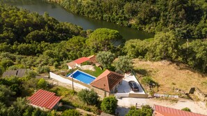 An aerial view of a property with a swimming pool, red-roofed buildings, and a surrounding forested area. - Casa Douro River - Douro Valley (Baião)