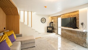 A modern living room with a sofa, a flat-screen TV, a stone fireplace, and a wooden slatted wall. - Casa Douro River - Douro Valley (Baião)