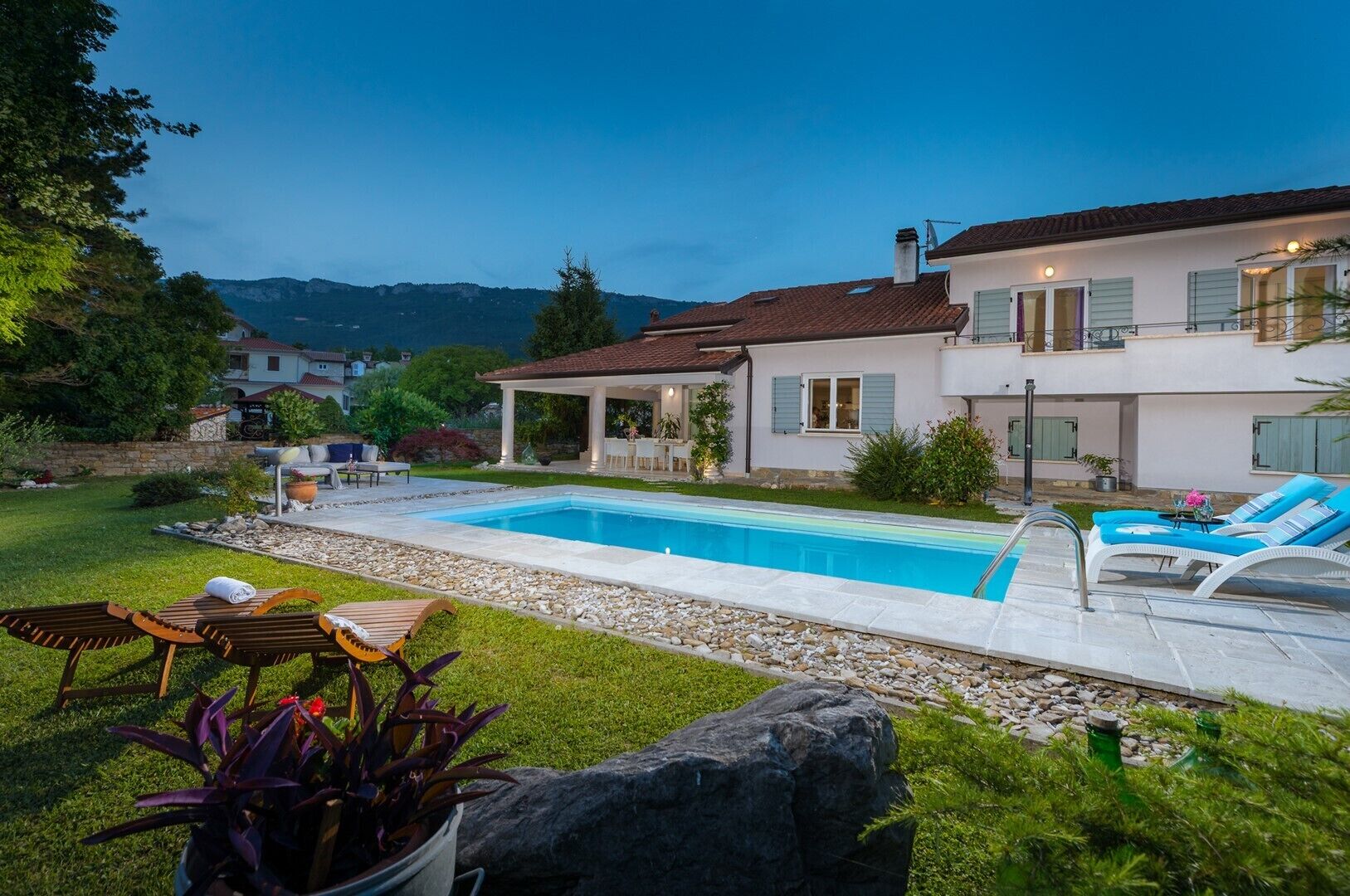 Ein modernes Haus mit Swimmingpool, Sitzgelegenheit im Freien und einem Garten.