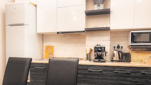 A modern kitchen with white cabinets, a black countertop, and a dining area with a marble table and black chairs.