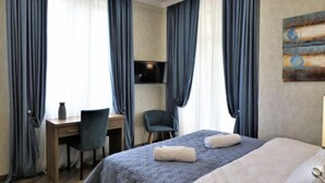 A hotel room with a bed, a desk, a chair, and a TV.