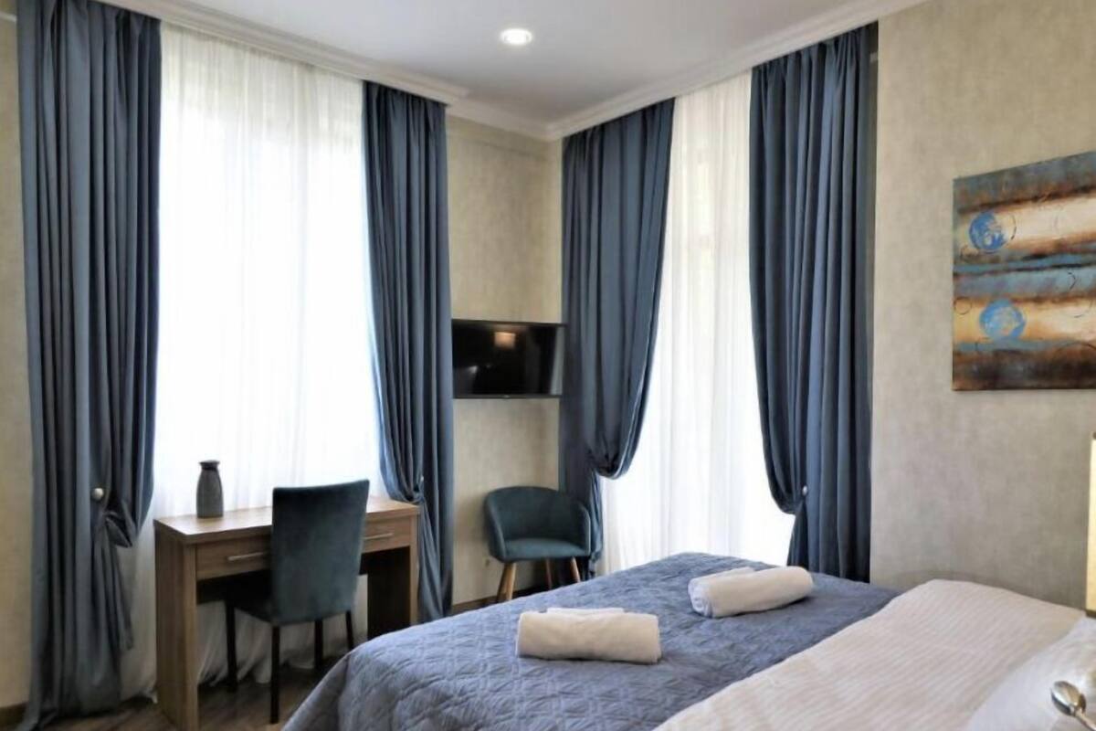 A hotel room with a bed, a desk, a chair, and a TV.