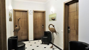 A hallway with three wooden doors, a black chair, and a decorative bird sculpture.