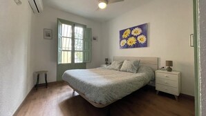 A bedroom with a bed, a nightstand, a ceiling fan, and a window with shutters. - La casita del Marqués (Alicante)