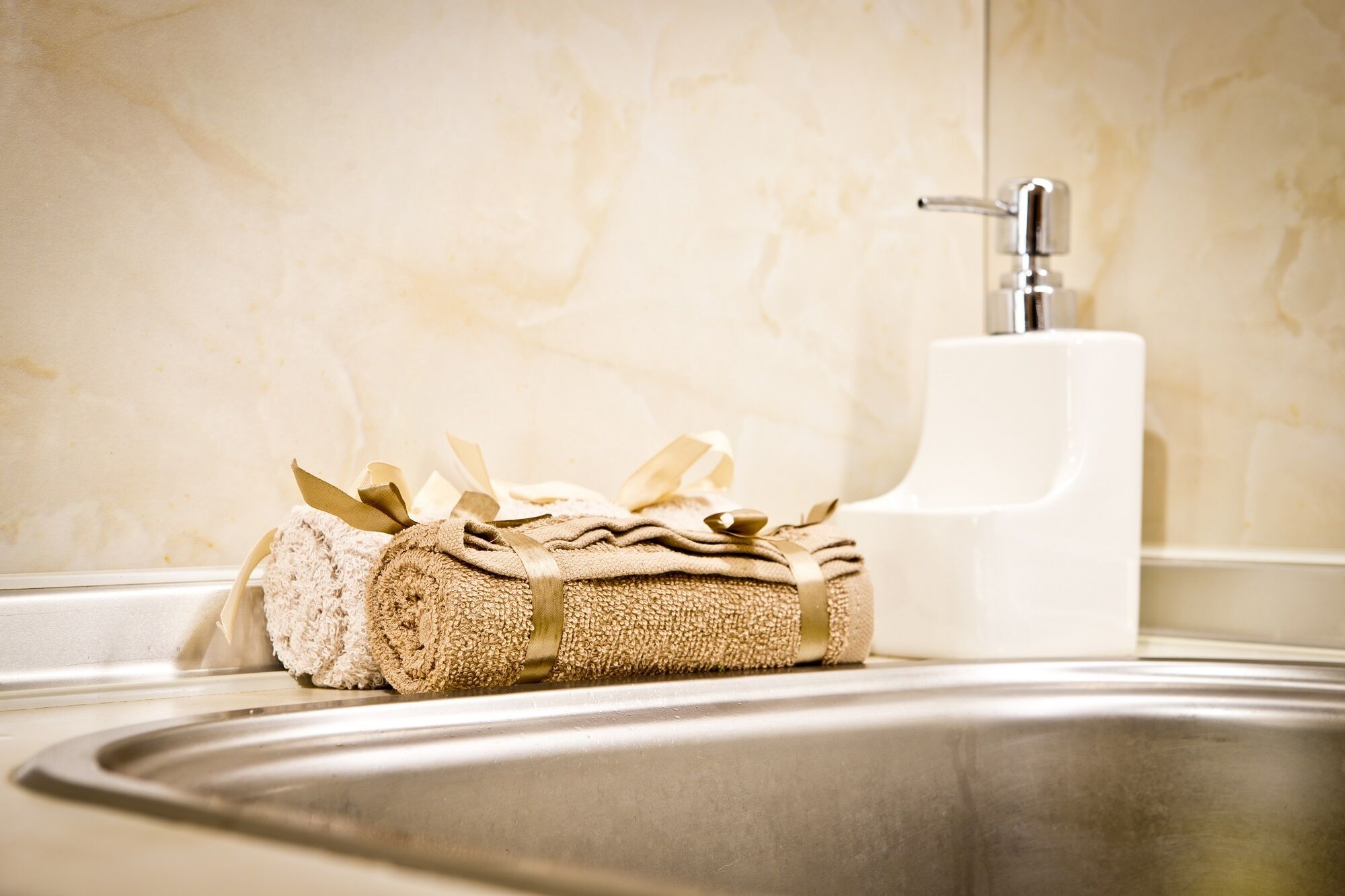 A bathroom with a sink, a towel, and a soap dispenser.