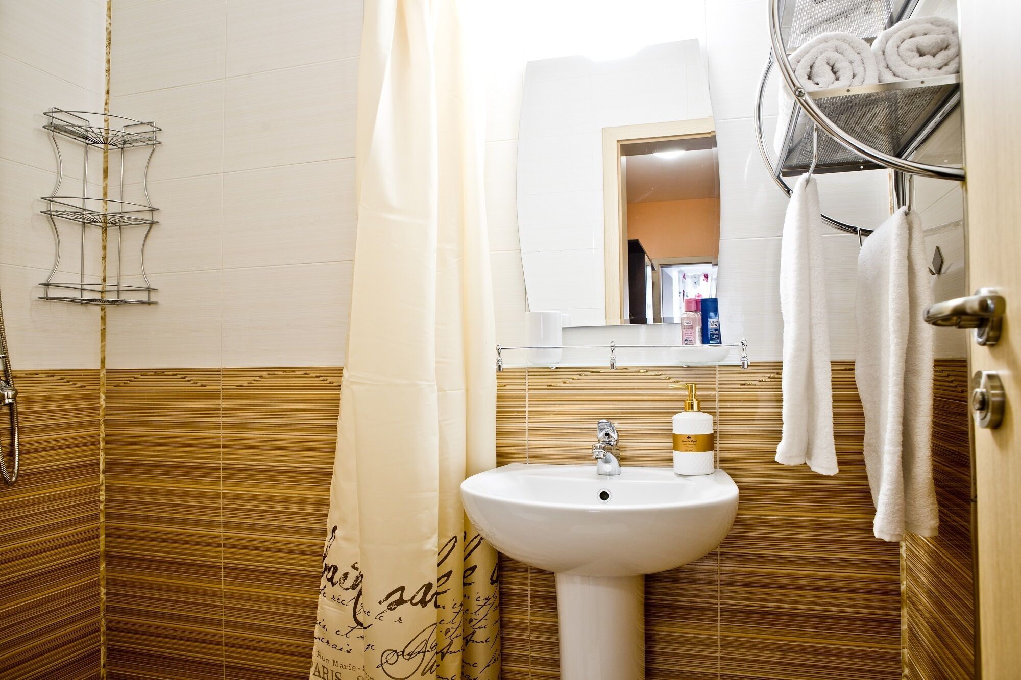 A bathroom with a white sink, a mirror above it, and a towel rack with towels.
