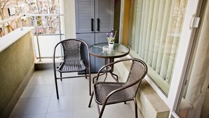 Ein Balkon mit zwei Korbstühlen, einem kleinen runden Tisch und einem Blumentopf.
