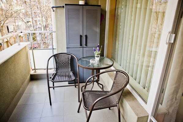 A balcony with two wicker chairs, a small round table, and a potted plant.