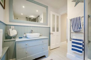 A bathroom with a white sink, a mirror, and a towel rack. - Mesmerising sea views above the beach Cornwall.

 (Torpoint)