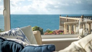 Un balcon donnant sur la mer, avec une balustrade et une porte vitrée.