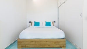 A bedroom with a wooden bed frame, white bedding, and teal pillows. - Nisida View Apartment (Pozzuoli)