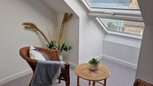 En hyggelig balkon med fletmøbler, et rundt bord og en potteplante.